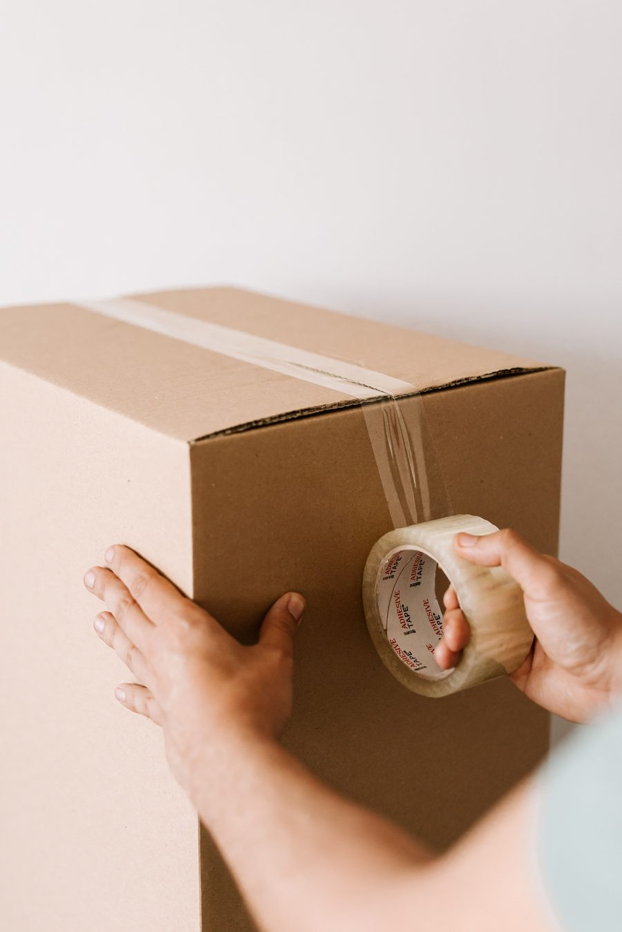 Hands carefully sealing a moving box